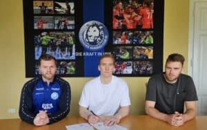 Trainer Gunnarsson und Gutbrod sitzen mit Neuzugang Gislason bei der Vertragsunterschrift