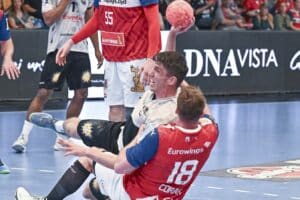 Frederik Ladefoged wird am Kreis vom Abwehrspieler von der Seite Richtung Boden gezogen, setzt dennoch mit dem rechten Arm zum Wurf an.